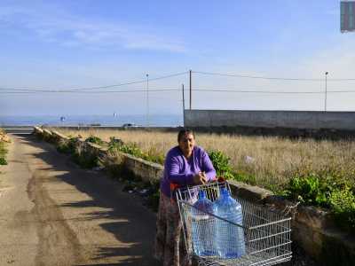 Ritornando indietro incrociamo un�anziana signora che guida un carrello da supermercato occupato da damigiane colme d�acqua